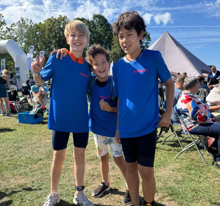 Drie lachende kinderen van Tri for Kids in blauwe AuRigoleau-shirts
