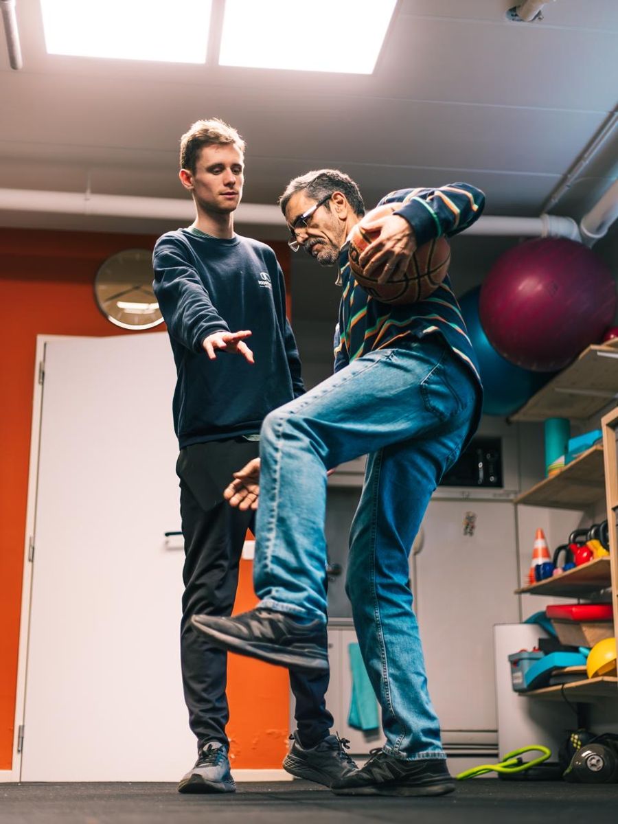 Lars De Donder begeleidt een patiënt bij een evenwichtsoefening met een bal